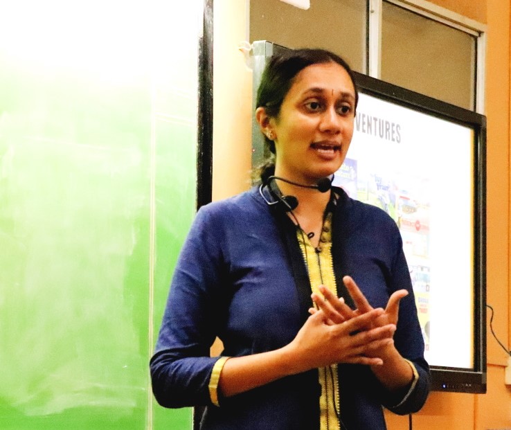 Varsha Seshan with collar mic in front of a screen displaying the railway adventures