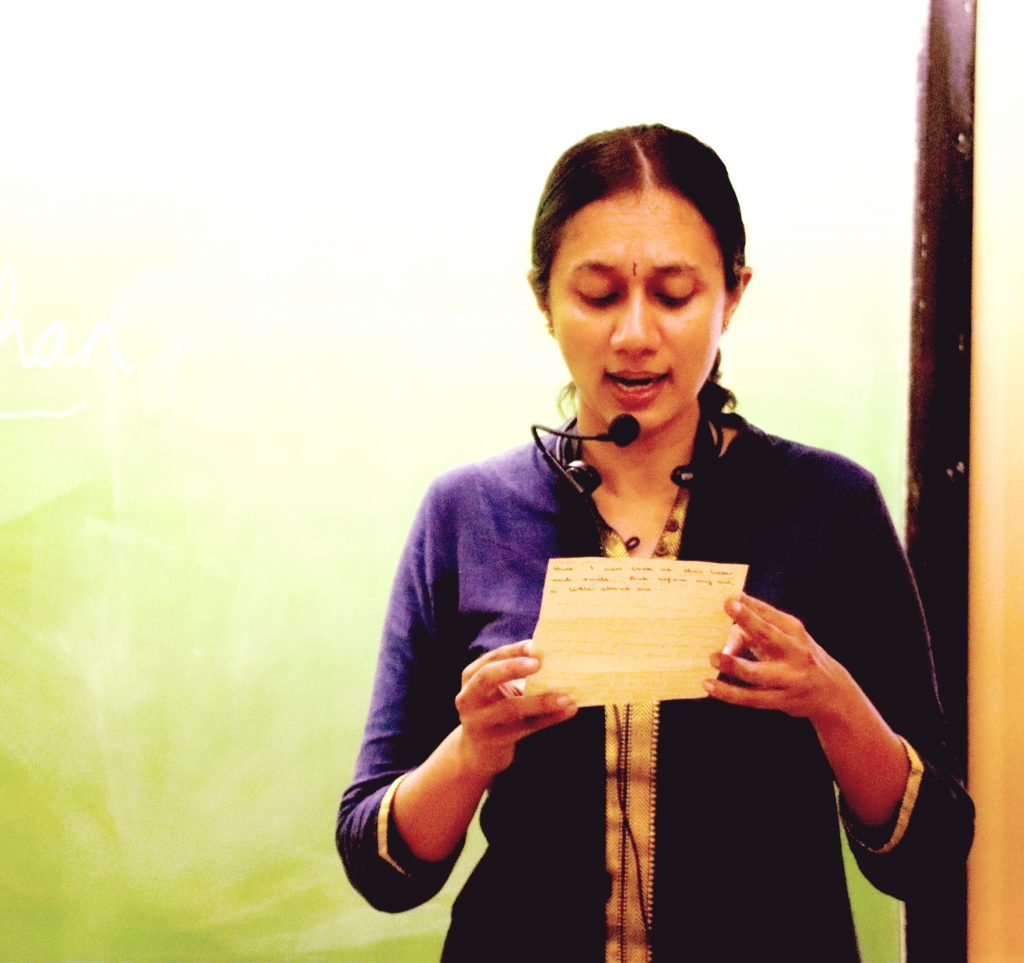 Varsha Seshan with a collar mic reading out a handwritten letter