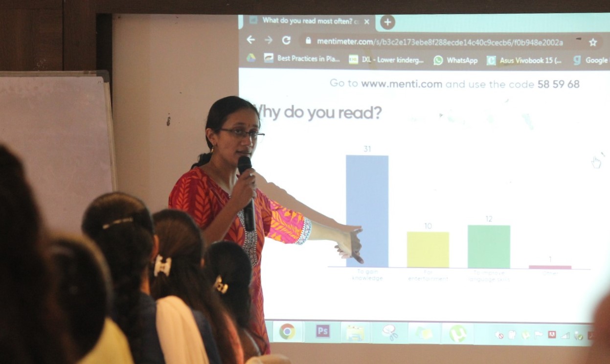 Varsha Seshan pointing to a bar graph which says 'Why do you read?'