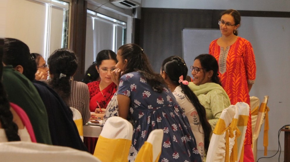 Librarians sitting at a table, discussing ideas. Varsha Seshan watching