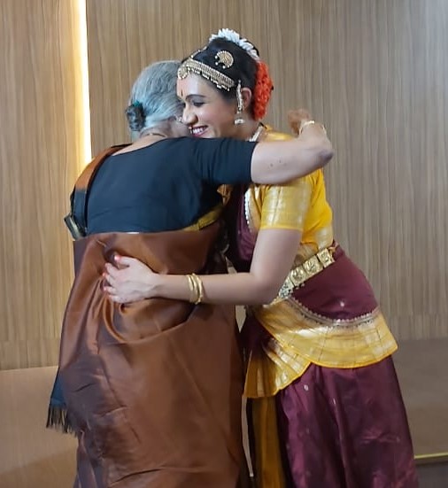 An older person hugging Varsha in dance costume